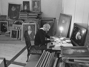 Die Fotografie zeigt Hans Häberli an einem Tisch arbeitend. Er ist umgeben von Bildportraits.