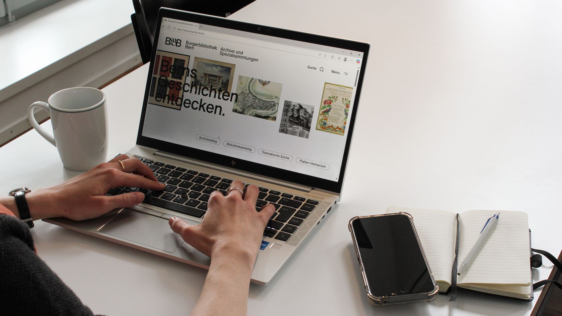 Eine Person, welche die Webseite der Burgerbibliothek Bern an einem Laptop besucht.